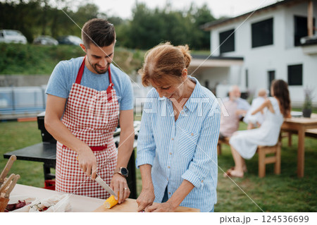 Adult son and mother preparing food for a family barbecue. Adult son and mother preparing food for a family barbecue. 124536699