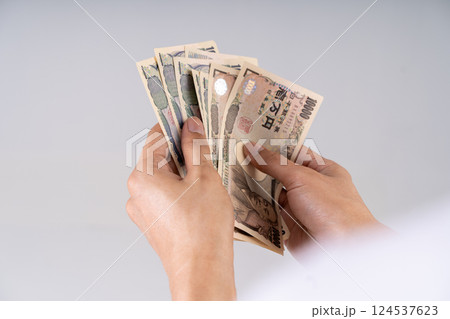 Detailed shot of Yen banknotes being counted: Illustrates financial decision-making and monetary interactions in Japanese economy 124537623