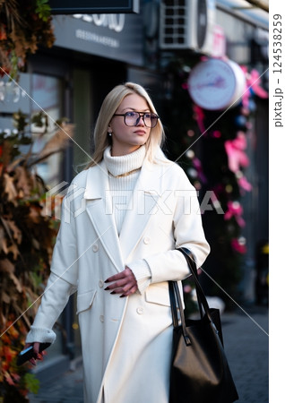 Elegant young woman strolls through a fashionable street adorned with fall foliage during a crisp afternoon in a vibrant urban area Elegant young woman strolls through a fashionable street adorned with fall foliage during a crisp afternoon in a vibrant urban area 124538259