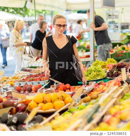 Woman buying fruits and vegetables at local food market. Market stall with variety of organic vegetable. Woman buying fruits and vegetables at local food market. Market stall with variety of organic vegetable. 124538631