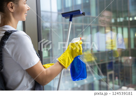Young woman from cleaning team cleaning the window in the office Young woman from cleaning team cleaning the window in the office 124539181
