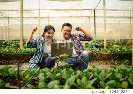 Happy farmers celebrating success in smart farming while viewing results on a laptop 124540274