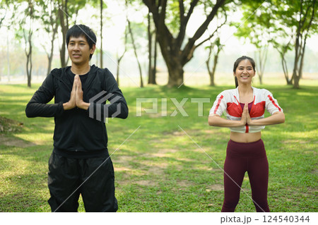 Young couple enjoy a morning yoga session together in a green park 124540344