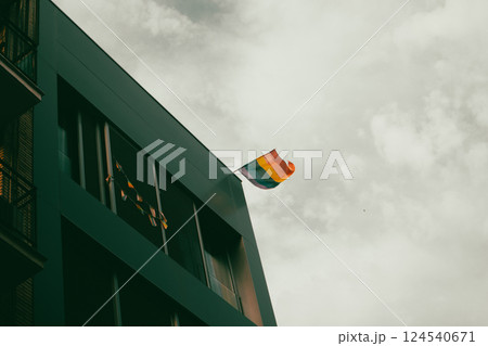 A multicolored LGBT flag on a modern building corner against sky. Diversity, gay minority, pride month symbol. Lesbians, gays community. Pride month. A multicolored LGBT flag on a modern building corner against sky. Diversity, gay minority, pride month symbol. Lesbians, gays community. Pride month. 124540671