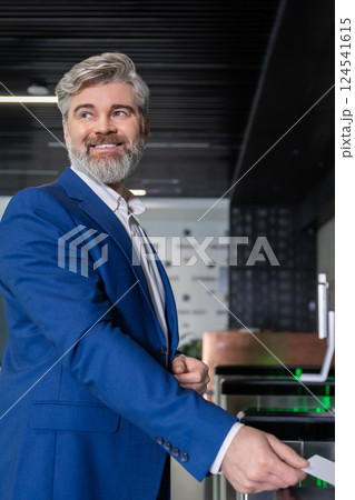 Gray-haired mature business man in dark-blue suit entering office with an access card Gray-haired mature business man in dark-blue suit entering office with an access card 124541615