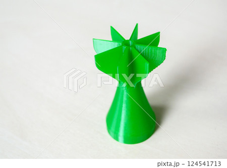 Prototype model of rocket bomb tip printed on 3D printer. Small models of tail fins, tail cone printed on 3D printer from molten green plastic on table. New modern printing 3D printing technology 124541713