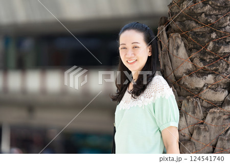 Aa Asian stylish woman with long hair and green blue dress is standing there pleasantly grinning. 124541740