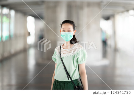 Aa Asian stylish woman with long hair and green blue dress is standing there pleasantly grinning. Aa Asian stylish woman with long hair and green blue dress is standing there pleasantly grinning. 124541750