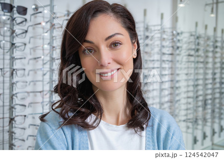 Pretty caucasian female client in a optic shop choosing eyeglasses Pretty caucasian female client in a optic shop choosing eyeglasses 124542047