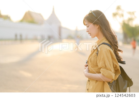 Traveler asian woman in her 30s stands bathed in the golden glow of sunset, embracing the freedom of exploration. on summer holiday weekend vacation trip in Bangkok, Thailand 124542603