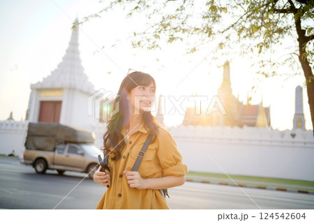 Traveler asian woman in her 30s stands bathed in the golden glow of sunset, embracing the freedom of exploration. on summer holiday weekend vacation trip in Bangkok, Thailand 124542604
