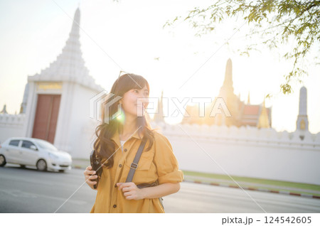 Traveler asian woman in her 30s stands bathed in the golden glow of sunset, embracing the freedom of exploration. on summer holiday weekend vacation trip in Bangkok, Thailand 124542605