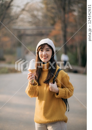 Cheerful Asian woman in yellow sweater enjoying tasty ice-cream indoors. Lifestyle portrait of a cute girl in a fashionable outfit, expressing joy and happiness. Cheerful Asian woman in yellow sweater enjoying tasty ice-cream indoors. Lifestyle portrait of a cute girl in a fashionable outfit, expressing joy and happiness. 124542631