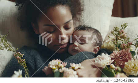 Tender moment on mother's day, african american mother cuddling baby surrounded by flowers. concept of maternal love, family bonding, parenthood, woman holding child 124542860