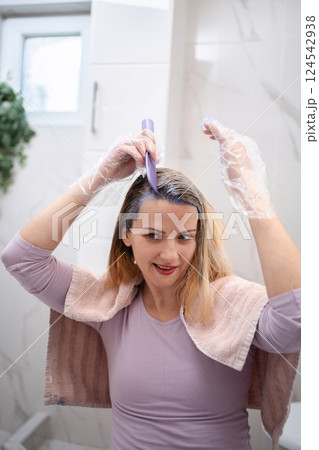 Woman dyeing her hair purple with a brush in the bathroom 124542938