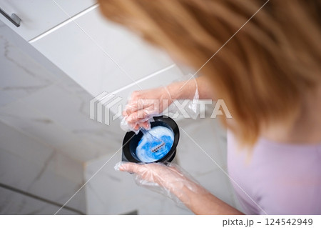 Hairdresser preparing blue dye for hair coloring in a bowl, wearing gloves 124542949