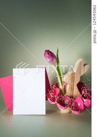 White empty paper note template mock up postcard Easter holiday decoration from sustainable materials pink colored egg shell wooden bunny vase decor with fresh tulip flower. Copy space Diy do it 124543062