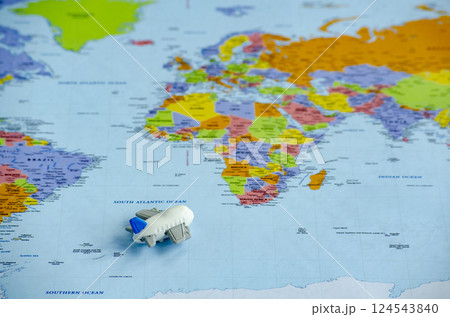 Top view of small toy airplane placed on a world map representing travel or global exploration. Travel and destination concept 124543840