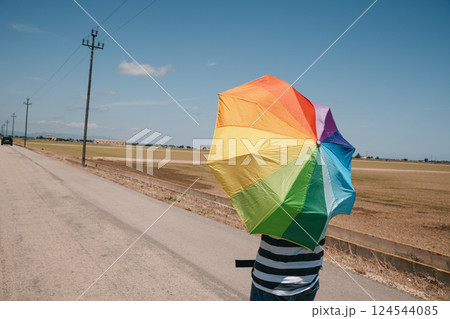 man carrying a rainbow umbrella on his shoulders man carrying a rainbow umbrella on his shoulders 124544085