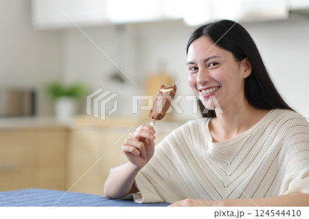 Happy asian woman holding ice cream looks at you Happy asian woman holding ice cream looks at you 124544410