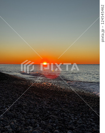 Sunset over rocky beach with soft waves and colorful sky 124545462
