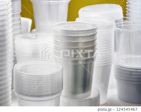 Clear plastic cups and containers stacked neatly on a table in a bright space suitable for events or gatherings Clear plastic cups and containers stacked neatly on a table in a bright space suitable for events or gatherings 124545467