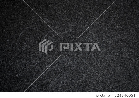 Dark textured surface featuring chalk board residue and scratches, showcasing signs of wear and age, creating a gritty, abstract background 124546051