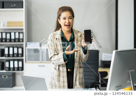 Happy nusinesswoman holding a smartphone, happy smiling, getting bonus money. 124546133