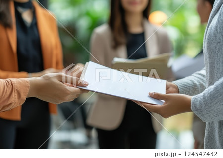 Manager Handing Booklet to Small Team of Employees in Modern Office Setting Manager Handing Booklet to Small Team of Employees in Modern Office Setting 124547432