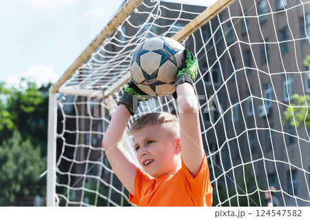 Goalkeeper boy catching soccer ball above his head. Goalkeeper boy catching soccer ball above his head. 124547582