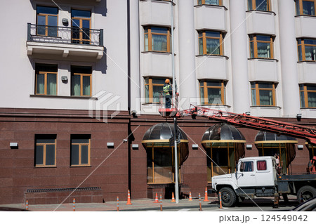 worker in a cradle inspecting facade of building. worker in a cradle inspecting facade of building. 124549042