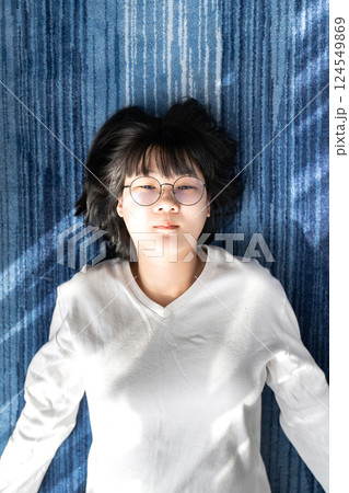 Cute short hair - glasses Asian woman laid on blue carpet. Cute short hair - glasses Asian woman laid on blue carpet. 124549869