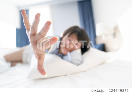 Abstract and Blurry Asian cute woman lying down on white pillow and bed then she raises up her hand to the camera. Abstract and Blurry Asian cute woman lying down on white pillow and bed then she raises up her hand to the camera. 124549873