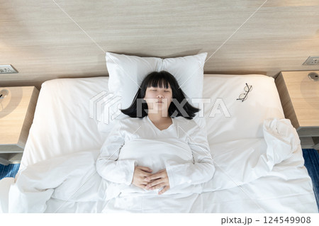 Asian woman sleeps on white bed after exhausted and tried all day. 124549908