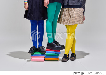 Three people in colorful tights stand atop stack of books, symbolizing collaborative learning and bright start to education. Back to school, development Three people in colorful tights stand atop stack of books, symbolizing collaborative learning and bright start to education. Back to school, development 124550589