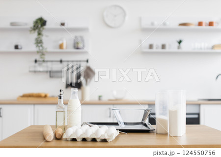 Ingredients arranged neatly on a kitchen counter in a modern interior, ready for baking. Minimalistic design promotes organization and functionality, with soft neutral tones. 124550756