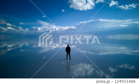 雲と空に包まれるウユニ塩湖とひとり佇む旅人の後ろ姿 雲と空に包まれるウユニ塩湖とひとり佇む旅人の後ろ姿 124551466