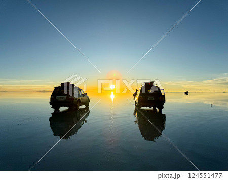 ウユニ塩湖で朝日を迎える四輪駆動車と旅人のシルエット 124551477