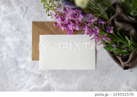 Handmade stationery with purple flowers and a brown envelope on a marble surface creating an inviting workspace atmosphere 124552570