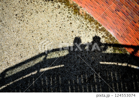 橋の上から地面に映る人影と手すりの影 124553074