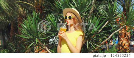 Summer vacation, tourism, happy young woman drinking fresh juice in straw tourist hat with palm tree 124553234