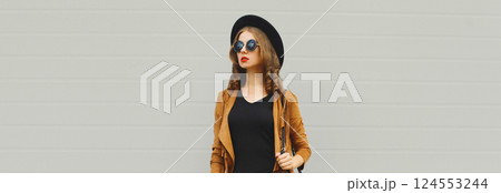 Beautiful stylish young woman posing with handbag in black hat, jacket, glasses on city street Beautiful stylish young woman posing with handbag in black hat, jacket, glasses on city street 124553244