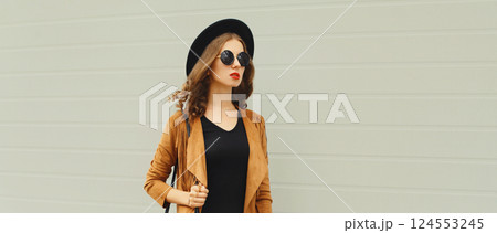 Beautiful stylish young woman posing with handbag in black hat, jacket, glasses on city street Beautiful stylish young woman posing with handbag in black hat, jacket, glasses on city street 124553245
