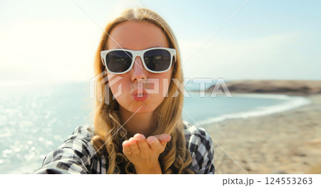Summer portrait happy woman taking selfie on phone blowing kiss on the beach on sea, summer vacation 124553263