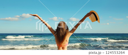 Summer vacation, beautiful happy woman in bikini swimsuit raising her hands up on the beach at sea 124553264