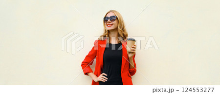 Stylish happy woman in red business suit with cup of coffee looking away stands on white background 124553277