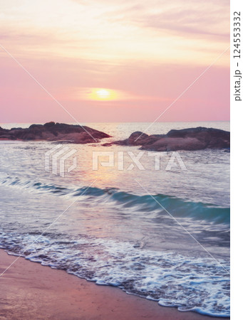 ailand - Turquoise waves of the sea wash over the sandy beach. Stones are visible in the water - a feature of the beaches of Khao Lak in Thailand. 124553332
