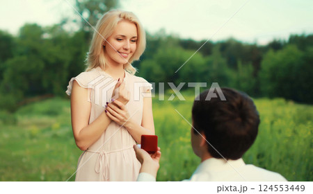 Wedding happy lovely young couple, man proposing a ring to his beloved woman outdoors in summer park 124553449