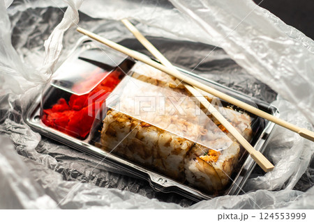 Sushi roll set in take away package in delivery bag. Food delivery concept. Food in plastic packaging Sushi roll set in take away package in delivery bag. Food delivery concept. Food in plastic packaging 124553999
