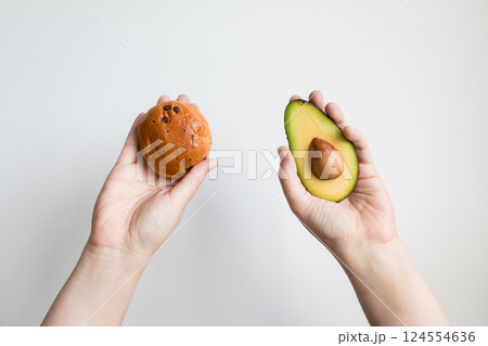 Hands holding avocado and cookie against white background Hands holding avocado and cookie against white background 124554636